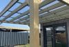 Pergola bois adossée avec toiture polycarbonate transparent sous ciel bleu