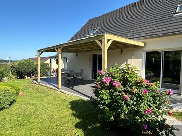 Pergola en bois adossée à une maison avec terrasse et mobilier de jardin