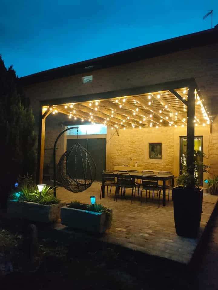 Pergola en bois avec éclairage, aménagée avec table et chaises pour repas extérieur