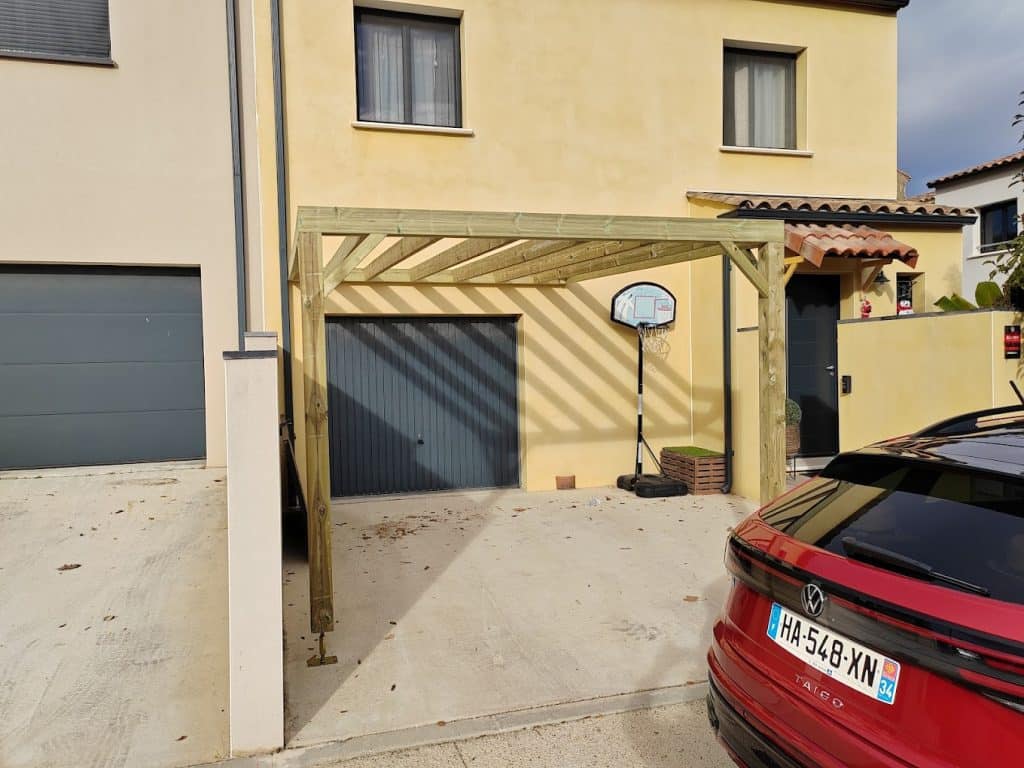 Pergola bois adossée à une maison avec garage, devant une voiture rouge
